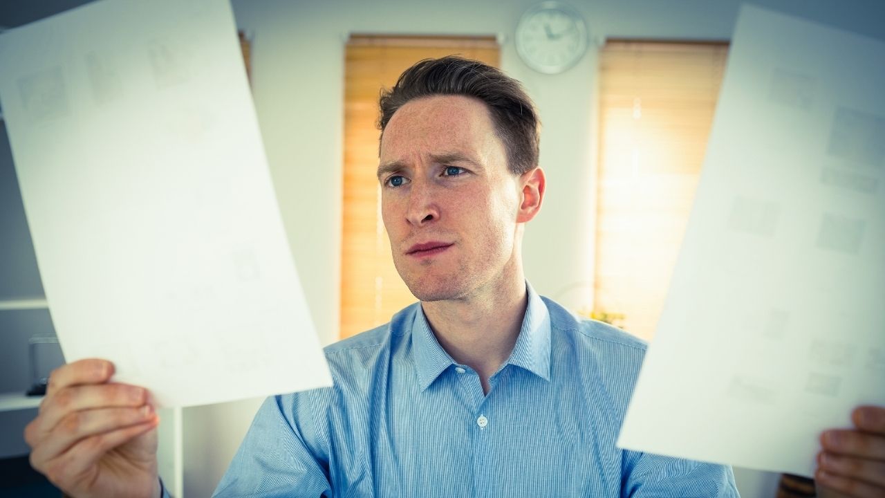 man looking at two pieces of paper
